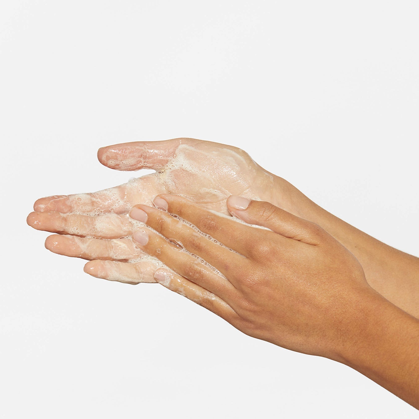Hands with soap lather on a plain background